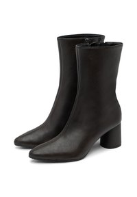 Un par de botas de tobillo de cuero negro texturizado con puntera puntiaguda y tacones de bloque, cierre lateral con cremallera, exhibidas sobre un fondo blanco.