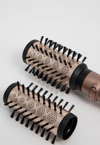 Deux embouts de brosse ronds en or métallique et noir. Les brosses présentent des poils allongés et un baril perforé pour une distribution de chaleur.