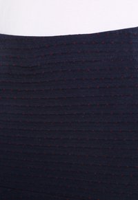 Tessuto a coste blu navy con piccoli pois rossi. Texture liscia con righe orizzontali. Adatto per abbigliamento casual o come strato.
