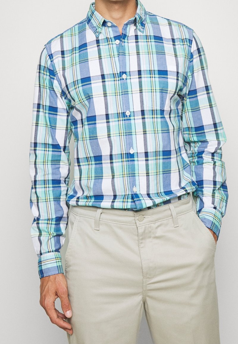 Gevouwen hemd in blauw, groen en witte stof; lichtgewicht katoenmix; lange mouwen; borstzak; gecombineerd met beige broek.