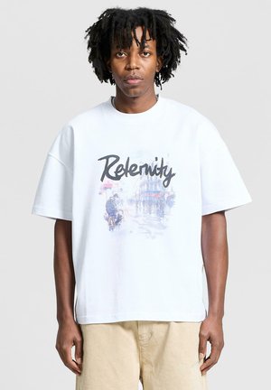 Witte oversized t-shirt met een grafische print van een straatbeeld en het woord "Releentity" in dikke zwarte letters. Korte mouwen.
