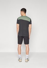 Herrkortärmad T-shirt med mörkgrå kropp och grön axelpanel. Sammanfogas med svarta shorts och grå sneakers. Strukturerad tyg.