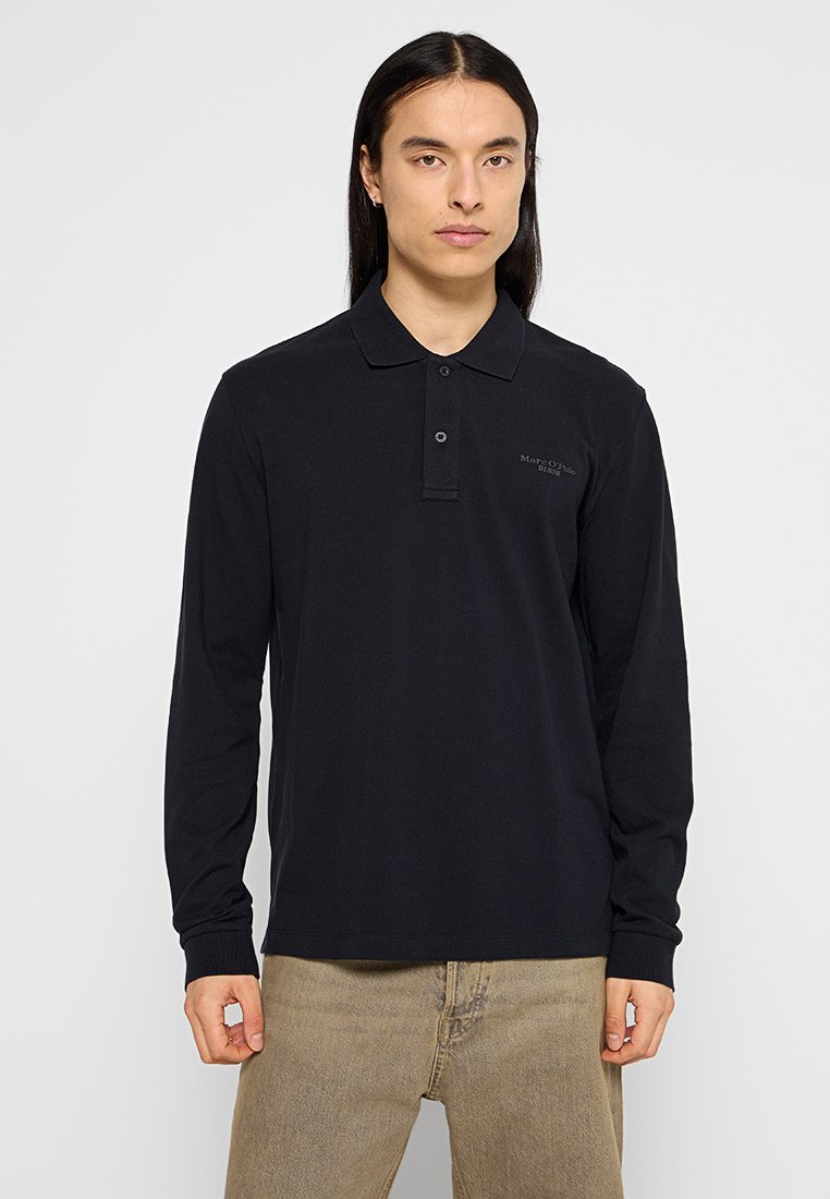 Schwarzes Langarm-Polohemd mit Kragen, ausgestattet mit einem dezenten Logodetail auf der Brust und gerippten Bündchen. Hergestellt aus strukturiertem Baumwollstoff.