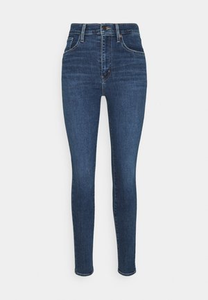 Tights jeans laget av mørkeblå denim. Høy midje med en jevn tekstur, med fem lommer og en frontknappfeste.