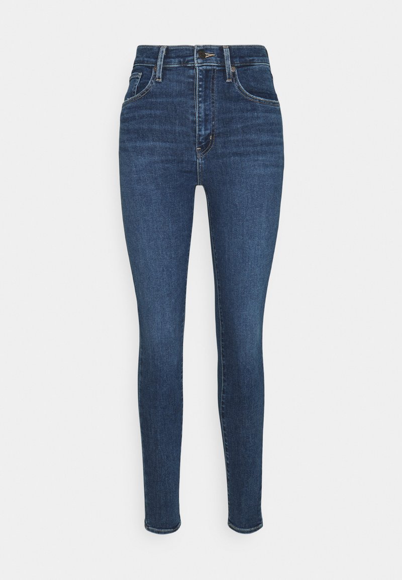 Jeans ajustados de denim azul oscuro. De talle alto con una textura suave, cuentan con cinco bolsillos y un cierre de botón en la parte delantera.