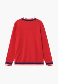 Czerwony sweter z długim rękawem wykonany z miękkiego materiału. Posiada żeberkowy kołnierz i mankiety w niebiesko-białe paski. Gładka tekstura, casualowy styl.
