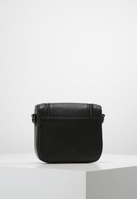 Borsa a tracolla in pelle nera con finitura testurizzata, dotata di chiusura con zip, forma rettangolare e tracolla regolabile.