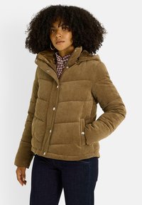 Chaqueta acolchada de pana marrón con capucha, botones a presión y bolsillos laterales. La tela tiene una textura acanalada y un diseño acolchado.