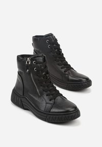 Bottines en cuir noir avec fermeture à lacets, zip latéral, semelle en caoutchouc et tige texturée. Design élégant avec un talon épais.