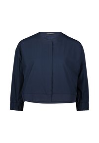 Blouse raccourcie marine en tissu lisse. Dotée d'un col rond, de manches longues avec des poignets élastiques, et d'une couture centrale sur le devant.