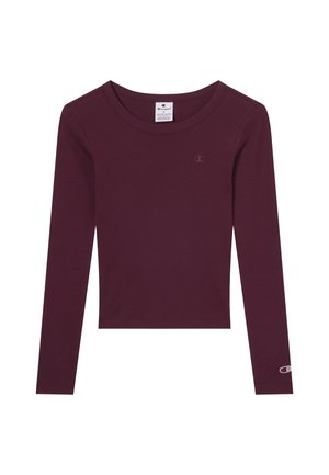 Haut court à manches longues de couleur violet foncé avec un col rond, petit logo Champion sur la poitrine et la manche, et étiquette de taille à l'intérieur du col.
