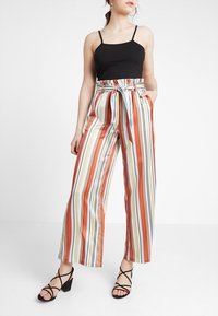 Pantalon large rayé à taille haute avec des rayures horizontales multicolores, doté d'une ceinture nouée à la taille et d'une finition satinée.