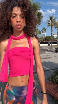Top senza maniche di un brillante colore rosa, con un dettaglio a collo drappeggiato, abbinato a una gonna fluida multicolore con motivi astratti.