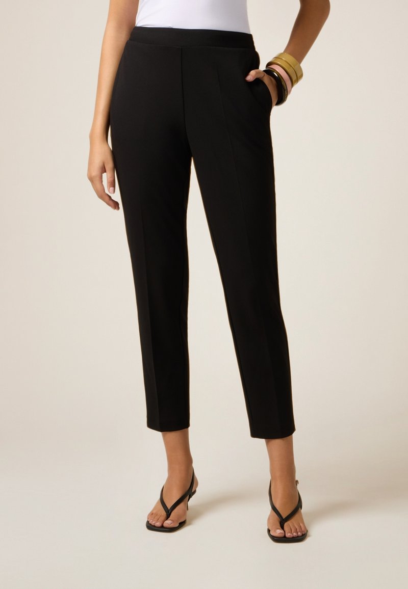 Pantaloni neri, sartoriali, con una vestibilità slim, cintura elastica e tasche laterali. Tessuto liscio con una leggera lucentezza, lunghezza cropped sopra la caviglia.