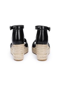 Sandales espadrilles en cuir noir avec un talon en jute tressé, une sangle de cheville ajustable et un design ouvert avec des découpes.
