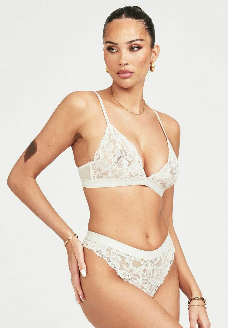 Kanten lingerieset in ivoorkleur. De bralette heeft florale details en verstelbare bandjes. Bijpassende slip met kantafwerking en logo-elastiek in de taille.
