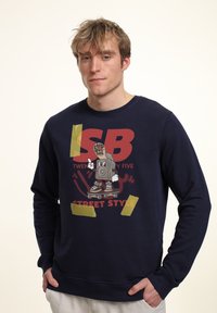 Felpa navy con grafica stampata raffigurante "SB" e "STREET STYLE", accentuata da nastro giallo. Composizione in cotone misto, collo a giro, maniche lunghe.