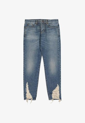 Jean en denim bleu avec un lavage délavé et de grandes déchirures usées sur les deux jambes basses près des ourlets.