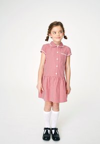 Punainen ruudullinen mekko lyhyillä hihoilla, napit edessä ja kaulus; sisältää volantti helman. Yhdistetty valkoisten polvisukat ja mustien kenkien kanssa.