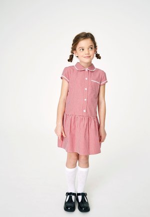 Rdeča vichy obleka s kratkimi rokavi, z gumbom spredaj in ovratnikom; ima naelektreno krilo. V combinatie z belimi do kolen segajočimi nogavicami in črnimi čevlji.