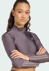 Dragkedjeträningsjacka i grått tyg, med hög krage, långa ärmar med randiga detaljer och en åtsittande design.