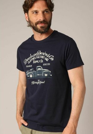 Marineblauwe katoenen t-shirt met korte mouwen, met een vintage vrachtwagenafbeelding en tekstprint in lichtcrème, ronde halslijn, relaxte pasvorm.