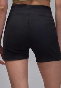 Svarta ribbade shorts med hög midja. Tillverkade av stretchigt tyg med en slät yta och rena sömmar, vilket ger en åtsittande siluett.
