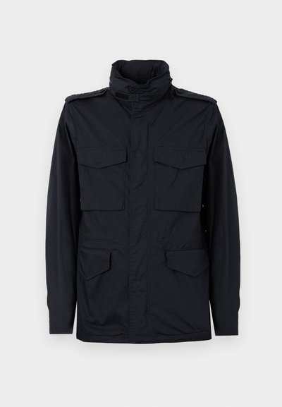 Veste noire de style militaire avec col montant et quatre poches à rabat, présentée sur un fond clair uni.