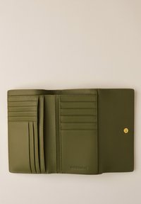 Portefeuille en cuir vert olive, pliable en trois, ouvert pour montrer plusieurs fentes pour cartes et une fermeture à pression sur un fond neutre.