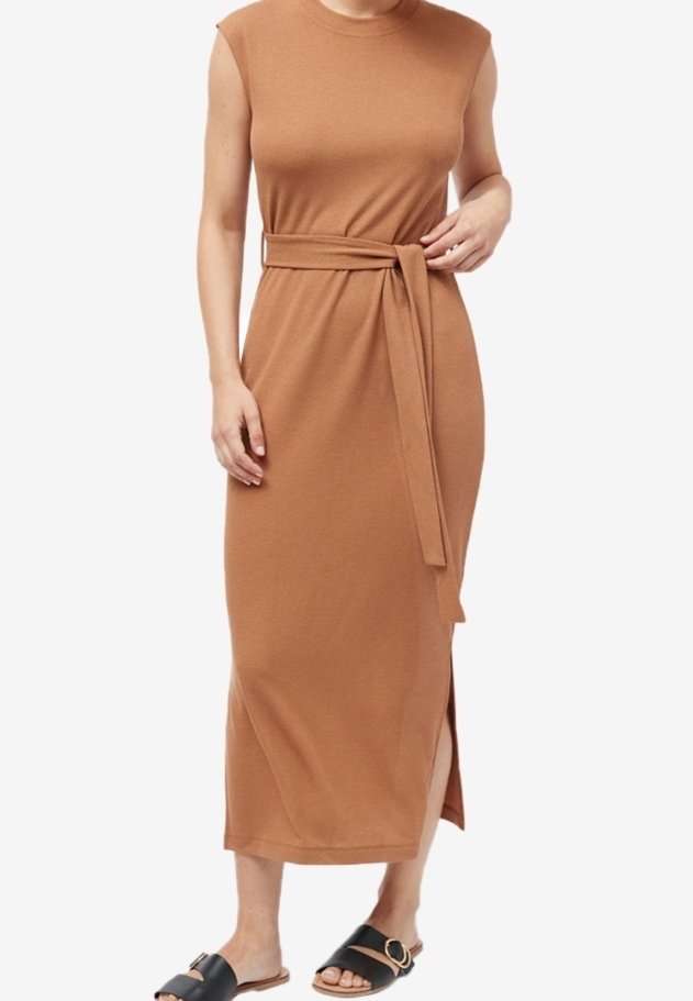 Brun midi-kjole med ærmeløs design, sideslids og taljebånd. Har en glat tekstur. Sammen med sorte slidesandaler.