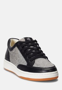 Svart och vit mönstrad sneaker med läder- och meshmaterial, rund tå, svarta snören och gummisula med orange detaljer.