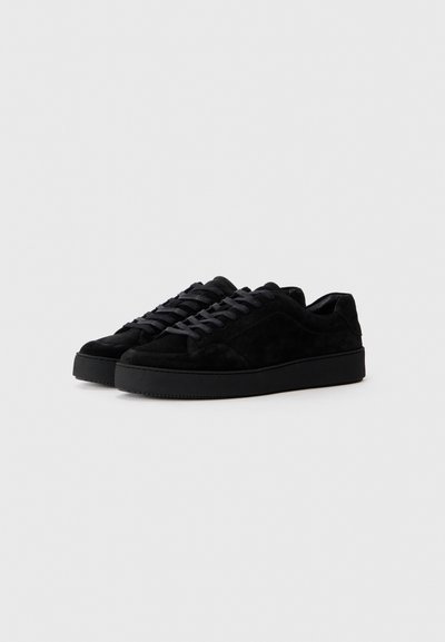 Sorte ruskinds sneakers med lav profil, rund tå, flad sort gummisål og matchende sorte snørebånd. Minimalistisk design.