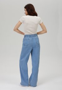 Høytlivte, lyseblå denimjeans med avslappet passform og elastisk midjebånd. Bak har de to påsydde lommer og en jevn tekstur.