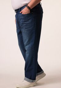 Mörkblå denimjeans med avslappnad passform, med uppvikta fållar, sidofickor och en mjuk textur. Matchas med vita sneakers.