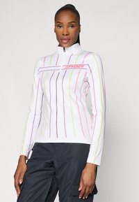 White long-sleeve top with a high collar, featuring vertical multicolored lines in pink, yellow, and purple. Front zip closure. Logo on chest.