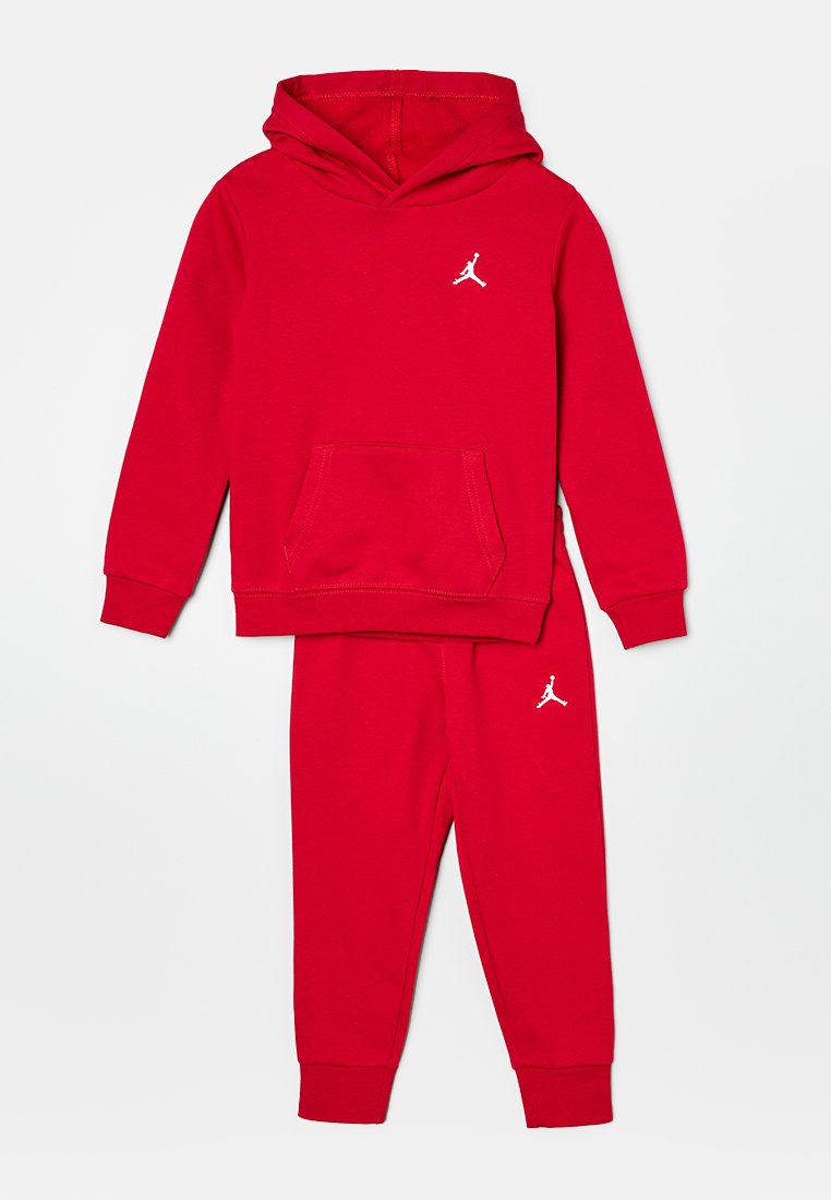 Sudadera de algodón roja con un bolsillo tipo canguro y un logo blanco en el frente, combinada con pantalones jogger rojos que tienen un pequeño logo en la pierna.