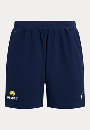 Pantalones cortos deportivos azul marino con el logo del US Open en amarillo y blanco en la pierna izquierda y el logo de Polo Ralph Lauren en la pierna derecha.