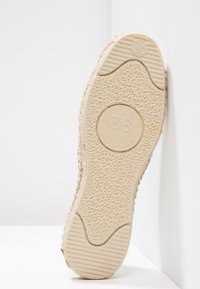 Sole of a shoe in light beige rubber with a textured surface, featuring '36' and 'MADE IN FRANCE' embossed, showing a curved shape.