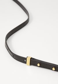 Cintura in pelle nera con una superficie liscia, caratterizzata da accessori in tonalità oro, una fibbia rettangolare e borchie decorative lungo il cinturino.