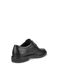 Schwarze Lederdressschuhe mit durchbrochenen Details, runder Spitze und niedriger schwarzer Gummisohle. Die Ferse ist strukturiert für besseren Halt und Stabilität.