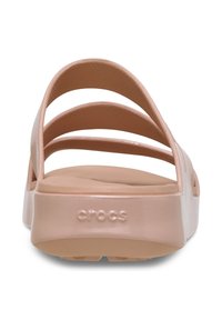 Pink Crocs slide sandals with four wide straps, a cushioned footbed, and a smooth, glossy finish. Brand logo embossed on heel.