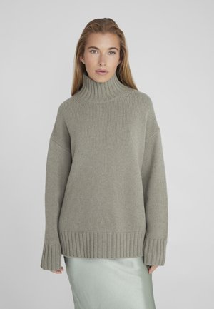 Khaki green knitted sweater with a high ribbed collar, dropped shoulders, and ribbed hem, paired with a satin mint green skirt.