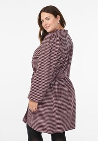 Bordowo-biała sukienka kopertowa w kratę, z długimi rękawami, paskiem w talii i rozkloszowanym krojem z bocznymi rozcięciami.