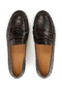 Mocassini in pelle sintetica nera effetto coccodrillo con punta rotonda e fasciatura decorativa sulla parte superiore. Soletta imbottita, suola piatta e texture liscia.