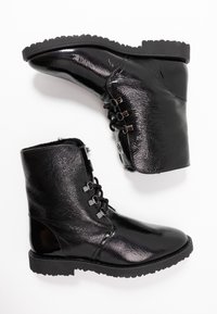 Botas negras hasta el tobillo con un acabado brillante y texturizado. Presenta un diseño de cordones, un panel lateral decorativo y una suela resistente con un patrón de agarre.