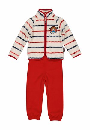 Børnefleece sæt med røde bukser og en hvid lynlåsjakke med røde og marineblå zigzag-striber samt et pigeansigt-patch på brystet.