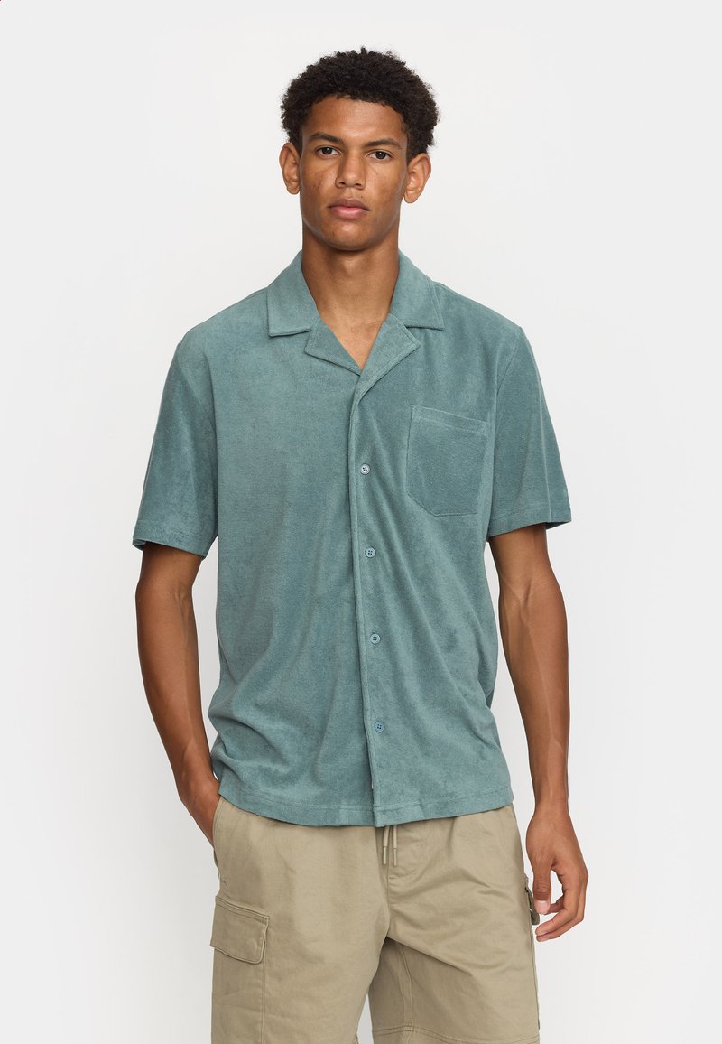 Lichtgroen kortloos shirt gemaakt van zachte stof, met een borstzak, knoopsluiting en een gekartelde kraag. Geschikt voor casual draag.