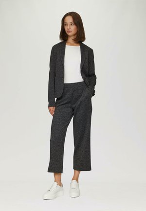 Donkergrijs, textuurig pak met een op maat gemaakte blazer en wijde broekspijpen, gecombineerd met witte sneakers. Eenvoudig, modern ontwerp.