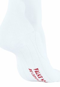 Calzino sportivo bianco con texture a coste e testo rosso "FAKE" sul fondo. Mostra una vestibilità aderente e un tallone rinforzato.