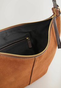 Sac à épaule en daim marron avec fermeture éclair dorée ouverte montrant l'intérieur en tissu noir et une petite poche zippée à l'intérieur.